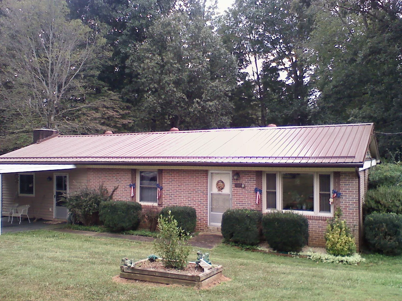 Bronze metal roof on a brick ranch home with a carport in Canton